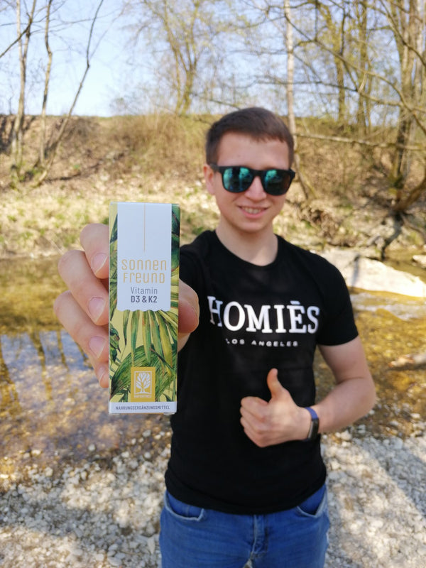 Zufriedener Kunde zeigt NATURTREU Sonnenfreund Vitamin D3 K2 Tropfen. 
