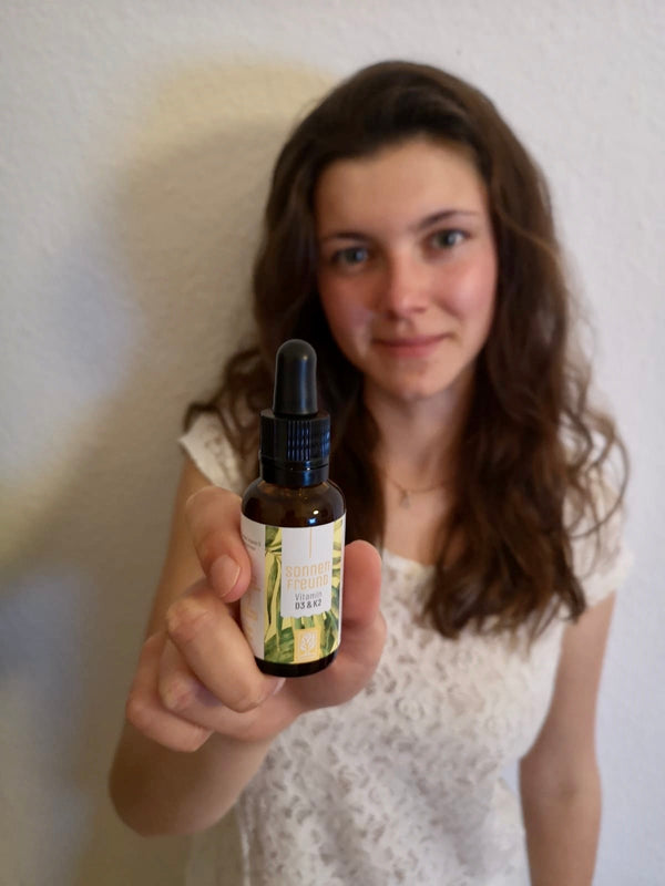 Zufriedene Kundin zeigt NATURTREU Sonnenfreund Vitamin D3 K2 Tropfen. 