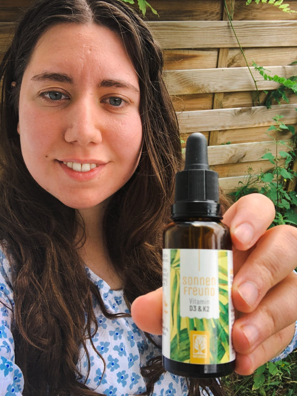 Zufriedene Kundin zeigt NATURTREU Sonnenfreund Vitamin D3 K2 Tropfen. 