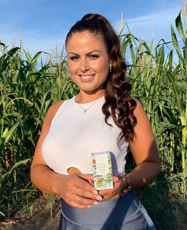 Zufriedene Kundin zeigt NATURTREU Florazauber Kapseln.