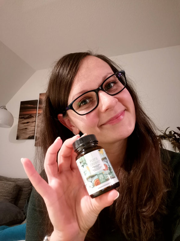 Zufriedene Kundin zeigt NATURTREU Florazauber Kapseln.