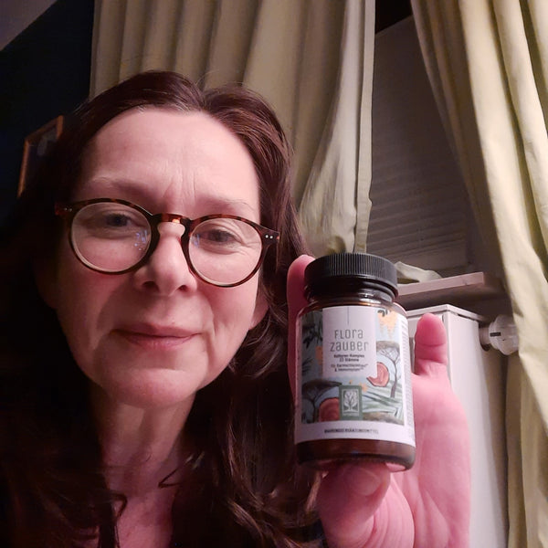 Zufriedene Kundin zeigt NATURTREU Florazauber Kapseln.
