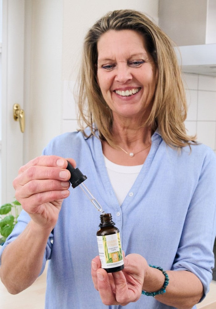 Frau dosiert NATURTREU SONNENFREUND Vitamin D3 K2 Tropfen – einfache tägliche Einnahme.